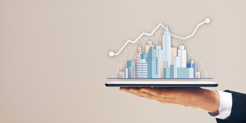 Poster - Hand holding tablet with a cityscape graphic and rising line chart on a plain background, symbolizing real estate and business growth.