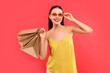 © New Africa - Smiling woman with shopping bags on red background