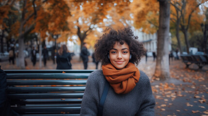 Beautiful woman sitting on park bench wearing earbud listening to music .