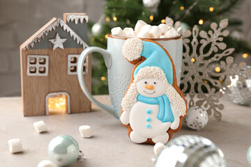 Wall Mural - Delicious cookie in shape of snowman, cup with cocoa and Christmas decor on light grey table