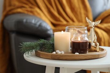 Wall Mural - Burning candles, fir branches and decorative deer on coffee table indoors, space for text. Christmas atmosphere