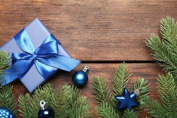 Poster - Fir tree branches with Christmas decor and gift box on wooden table, flat lay. Space for text