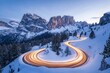 © Daria - Winter dawn long exposure of winding dolomite road with car light trails and snowy mountains