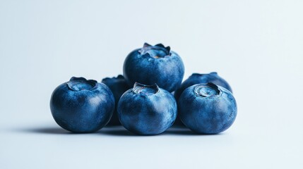 A close-up of fresh blueberries arranged on a light background.