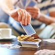 © peopleimages.com - Nursing home, hands and old woman with cards, biscuits and recreation with sweet treat. Closeup, pensioner and elderly person with snacks, activity and playing with game, tea break and retirement