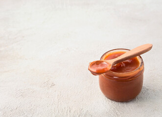 Caramel paste in jar with wooden spoon