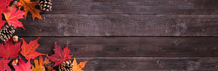 Aufkleber - Colorful autumn leaves, nuts and pine cones. Corner border over a rustic dark wood banner background. Above view with copy space.