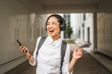 Wall Mural - japanese woman listen music on mobile phone between modern buildings