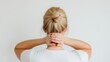 © Ben Trobat - Blonde woman holding back of neck in discomfort, rear view