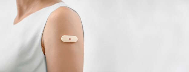 Person wearing a medical patch on arm for monitoring and treatment. Wearable device of real-time control of health through continuous glucose monitoring CGM system.