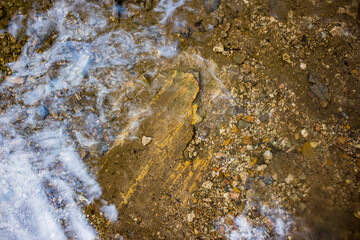 View of the surface of a shallow stream with stones at the bottom