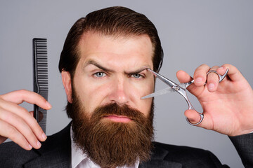 Wall Mural - Bearded man, bearded male. Portrait of stylish man beard with barber scissors and barber comb in barbershop. Bearded client visiting barber shop. Bearded man with scissors and barber comb. Beard care.