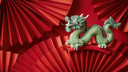 A green dragon figurine perched on red folded paper fans.