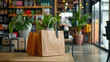 © khonkangrua - Eco-friendly paper shopping bags filled with potted plants, placed on a wooden table in a stylish, green-conscious retail store.