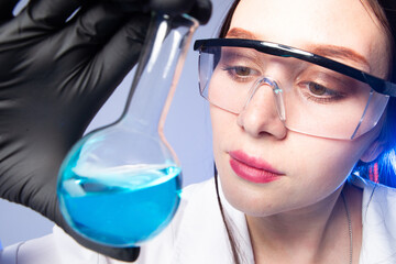 Poster - Laboratory technician with test tube. Woman scientist. Laboratory technician portrait. Girl in laboratory. Scientist holds flask with blue reagent. Career of chemist. Female biologist with glasses