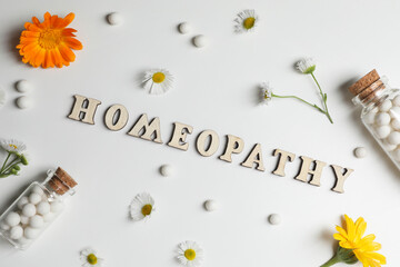 Word Homeopathy, pills and medicinal herbs on white background, flat lay