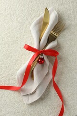 Poster - Christmas table setting. Cutlery, napkin, ribbon and bauble on light textured background, top view