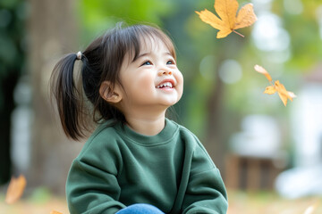 Wall Mural - Malay little girl smile wearing sweatshirt playing at sunny autumn park