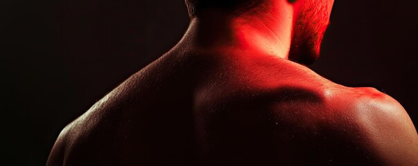 Poster - Dramatic close-up of a male back illuminated by red light, showcasing muscular definition and striking shadows.