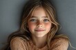 © Laisa - Portrait of a Joyful Young Girl Smiling at the Camera Against a Neutral Grey Background