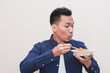 © Nurma - A Southeast Asian man wearing casual dress excited to eat a plate of fried noodles and holding a plate of what instant noodles with chopsticks, the man expression is cheerful