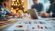 © Diffin - A businessman working on a laptop while analyzing charts at a desk, with a festive Christmas tree and decorations in the background.