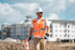 © Volodymyr - Construction site worker in helmet working outdoor. A builder in a safety hard hat at constructing buildings. Construction site worker with builders equipment. Man in hard hat on construction site.