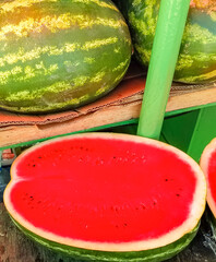 Half a ripe juicy watermelon on the background of whole watermelons at the farmer's market. Harvest organic fruits rich in moisture. Close-up image