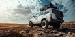 © Bambalino Studio - A white jeep is parked on a dirt road. The jeep has a large cargo rack on top of it. The sky is cloudy and the sun is shining