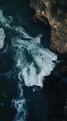 Poster - Aerial view of dark blue water crashing against rocky cliffs.