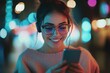 © Ahmed - Cheerful pretty young woman in cool eyeglasses and trendy wear walking on metropolis street with night lights enjoying online playlist songs in earphones and reading sms with good news on smartphone