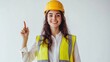 © Riko - Female construction worker in a yellow safety helmet and reflective vest pointing upward.