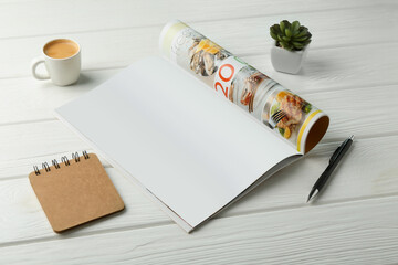 Canvas Print - Open magazine with blank page, coffee, plant and stationery on white wooden table. Mockup for design