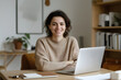 © MAX RETRI - Young happy business woman sitting at work desk with laptop. Smiling school professional online teacher coach advertising virtual distance students classes teaching remote education webinars. Portrait