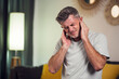 © Aleksej - Man covering his ears, stressed or unhappy because of loud music or too much noise. Indoors shot