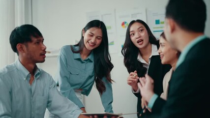 Poster - Four asian coworkers are discussing business strategy around a table in a brightly lit office. They are all smiling and engaged in the conversation