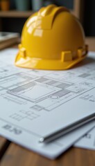 A close-up of a yellow hard hat resting on architectural blueprints, symbolizing construction, engineering, and project planning.