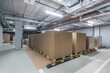 © alhim - Storage area filled with neatly stacked pallets of brown boxes in a well-lit warehouse