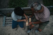 © qunica.com - An overhead view of a grandfather and grandson sitting on a bench, playing and bonding with a wooden game outdoors.