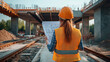 © Creative mind - Back view of female pofessional engineer analyzing blueprint at construction site. Civil engineer inspecting blueprint at infrastructure development.