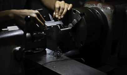 lathe in workshop. lathe worker uses a vernier caliper to measure distance.