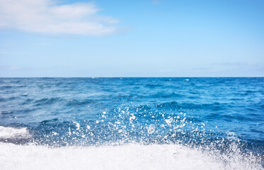 Blurred photo of sky and sea with splashing water, travel background.