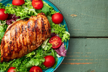 Wall Mural - Grilled chicken breast ( fillet ) with lattuce salad and cherry tomatoes . Top view