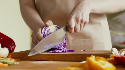 Poster - Woman chef cutting fresh red cabbage on kitchen board, close up