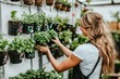 © Konstiantyn Zapylaie - Woman in greenhouse organizing potted plants on vertical garden wall