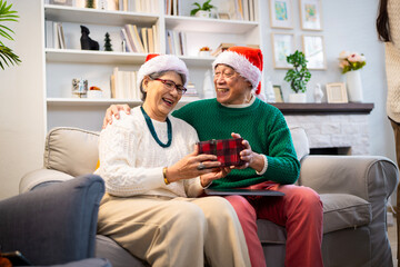 Wall Mural - Asian family on Christmas Day. Everyone is happy together in a Christmas themed room filled with presents and orange lights.