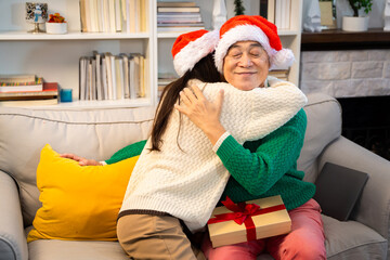 Asian family on Christmas Day. Everyone is happy together in a Christmas themed room filled with presents and orange lights.