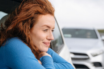 Young Woman Enjoys Peaceful Moment by Parked Car, Gazing Thoughtfully Into Distance