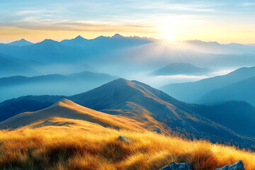 Landscape of majestic mountain ranges at sunrise, with golden sunlight casting soft rays over distant hills and valleys. The foreground consists of a grassy ridge covered in golden autumn hues.