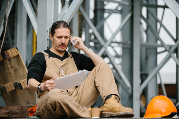 male construction worker in uniform resting and talking on the phone.